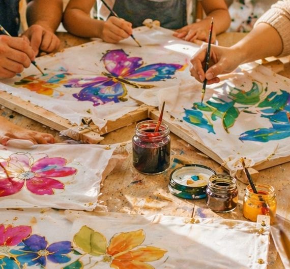 Kinder und Erwachsene gestalten bunte Seidenbilder im Seidenmalerei Kurs in Köln