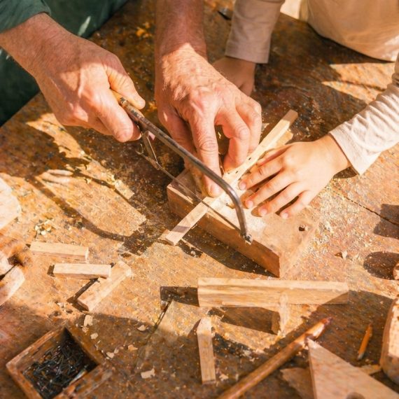 Eltern und Kind arbeiten mit Säge und Holz im kreativen Werkkurs in Köln