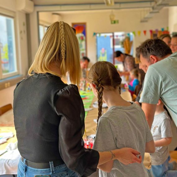 Erwachsene Begleitperson unterstützt ein Kind beim kreativen Arbeiten im Familienkurs in Köln