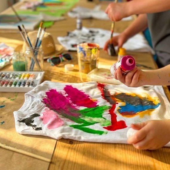 Kind gestaltet Textilien mit Farben im Sommerferienkurs Kreativmäuse der Kölner Kinderwerkstatt in Köln.