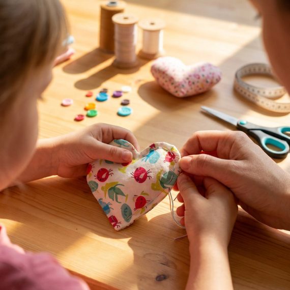 Kind und Begleitperson nähen gemeinsam ein Stoffherz im Familienkurs der Kölner Kinderwerkstatt in Köln