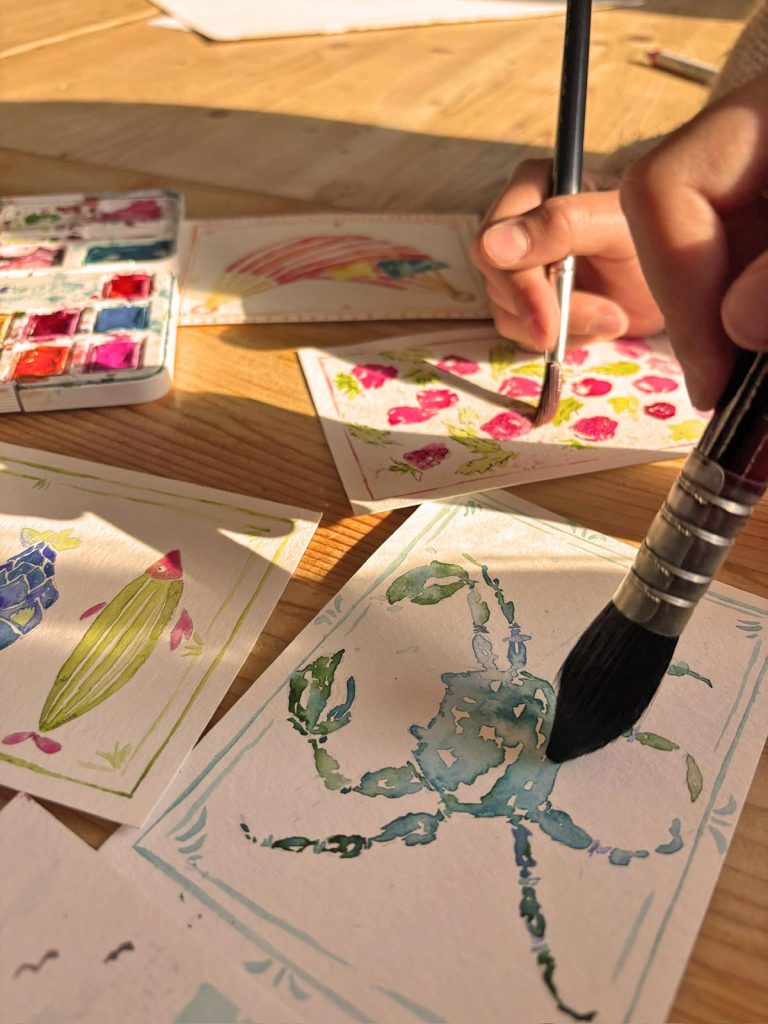 Kinderhände malen mit Aquarellfarben und Pinseln kleine Kunstwerke im Malkurs der Kölner Kinderwerkstatt in Köln