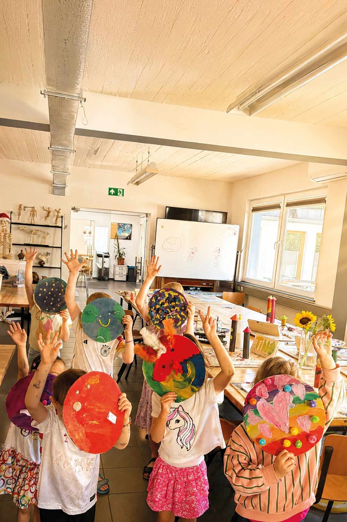 Kinder zeigen bunte selbstgestaltete Bastelarbeiten im Kurs Malen & Selbstständigkeit der Kölner Kinderwerkstatt in Köln